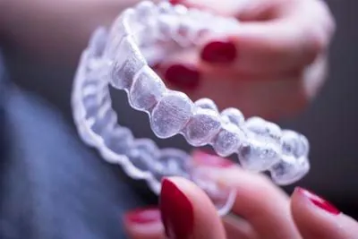 closeup of a woman holding her Invisalign clear aligners